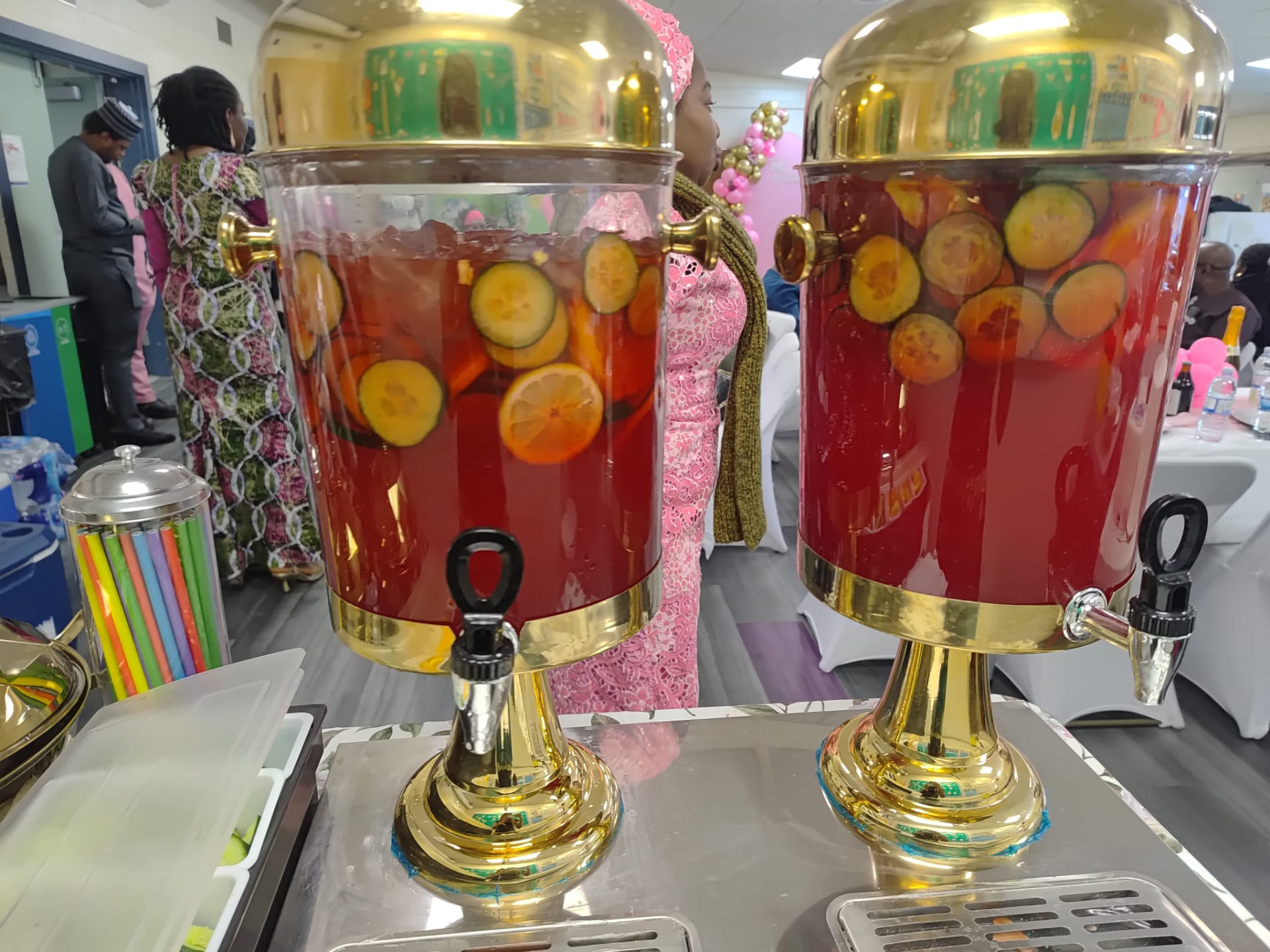 Two gold drink dispensers of fruit punch at a party